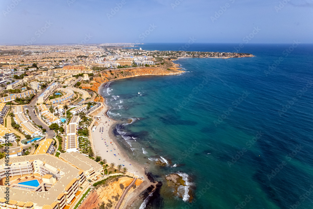 Aerial drone point of view Dehesa de Campoamor on the Costa Blanca of Spanish tourist resort, sandy beach coastline and blue-green waters of Mediterranean Sea. Summer holidays concept. Europe, Spain