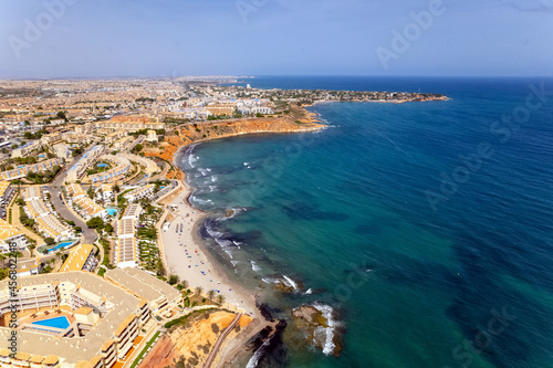 Aerial drone point of view Dehesa de Campoamor on the Costa Blanca of Spanish tourist resort, sandy beach coastline and blue-green waters of Mediterranean Sea. Summer holidays concept. Europe, Spain