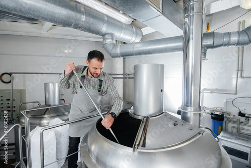 Картината върху платно A young male brewer is engaged in the brewing process in a small brewery