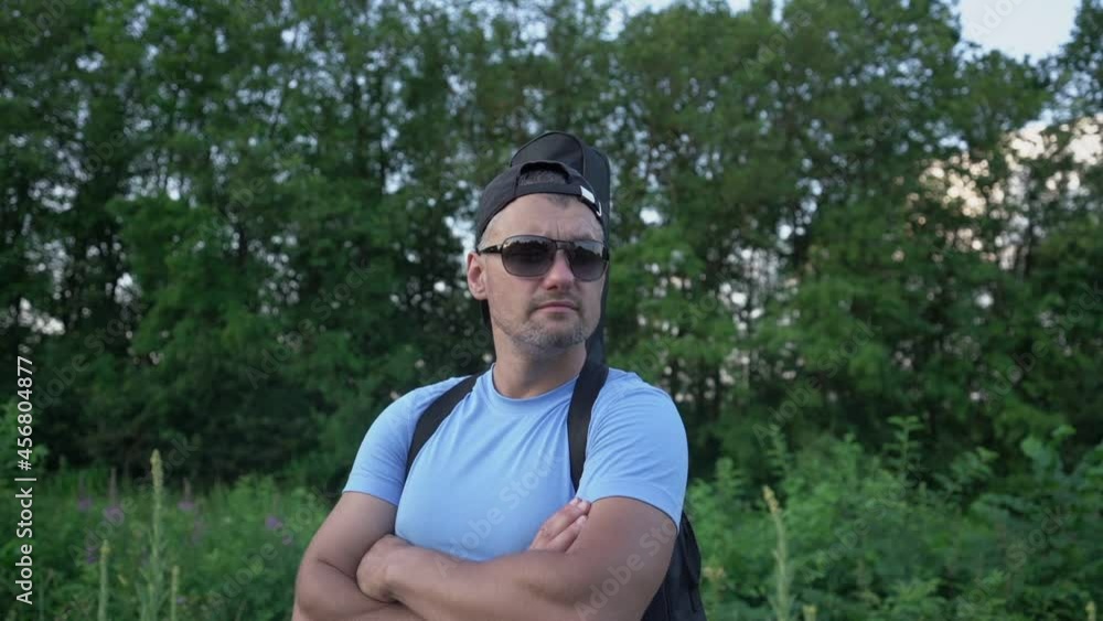 attractive authentic man in sunglasses with guitar stands in nature in summer and looks around outdoor attractive authentic man in sunglasses with guitar stands in nature in summer and looks around outdoor
