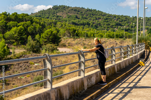 A woman near the railings of a dam of Algar del Palancia on a sunny day photo