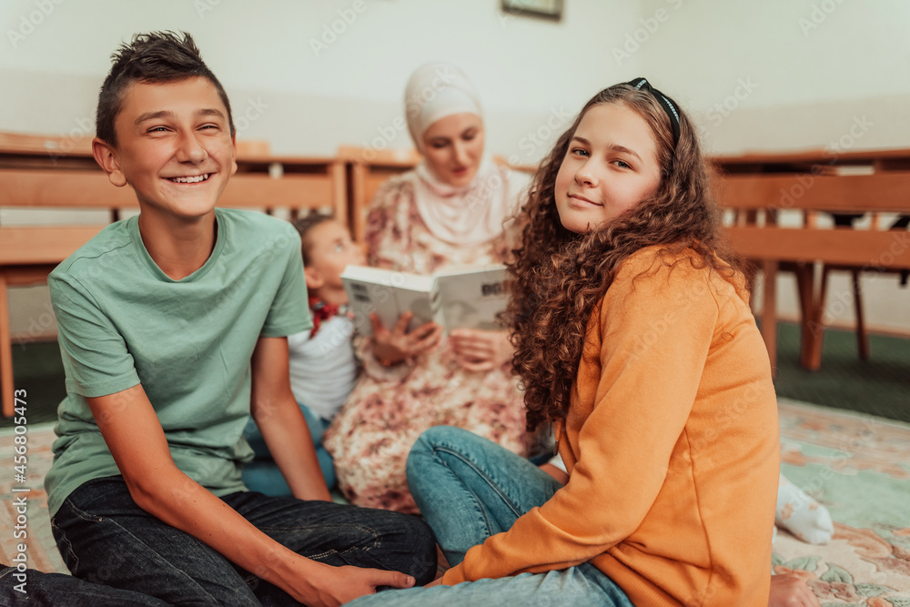Female teacher helps school kids to finish they lesson.They sitting all together on floor.Selective focus Female teacher helps school kids to finish they lesson.They sitting all together on floor.Selective focus