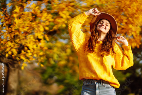 Young woman in a yellow sweater and jeans resting in nature. Fashion, style concept. People, lifestyle, relaxation and vacations concept.