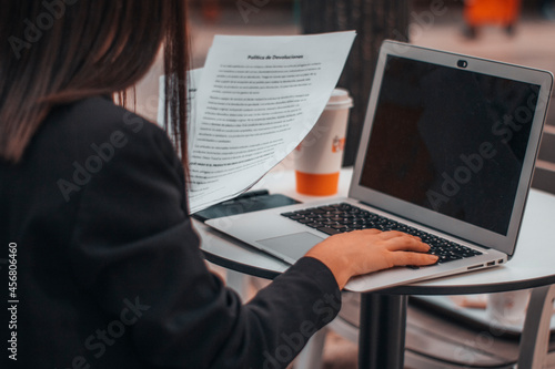 Abogada con seriedad escribiendo ideas y planteamientos en su ordenador laptop en una cafeteria de su ciudad tomando café por la mañana para terminar su trabajo photo