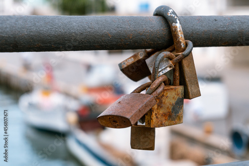 Rusty padlocks hooked together on a metal bar, with an out of focus background.