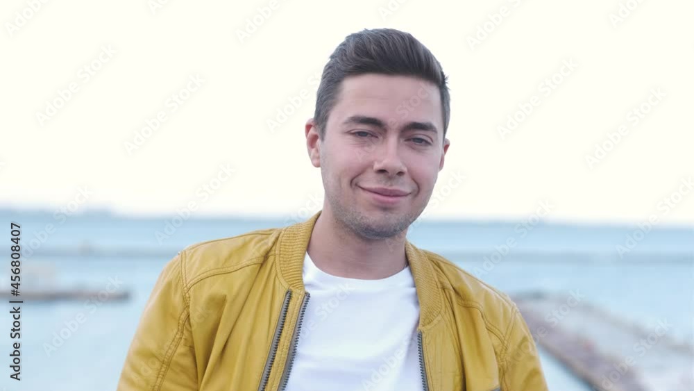 Close up portrait of handsome man in yellow jacket walking outdoors. Male model posing on camera on the street Close up portrait of handsome man in yellow jacket walking outdoors. Male model posing on camera on the street