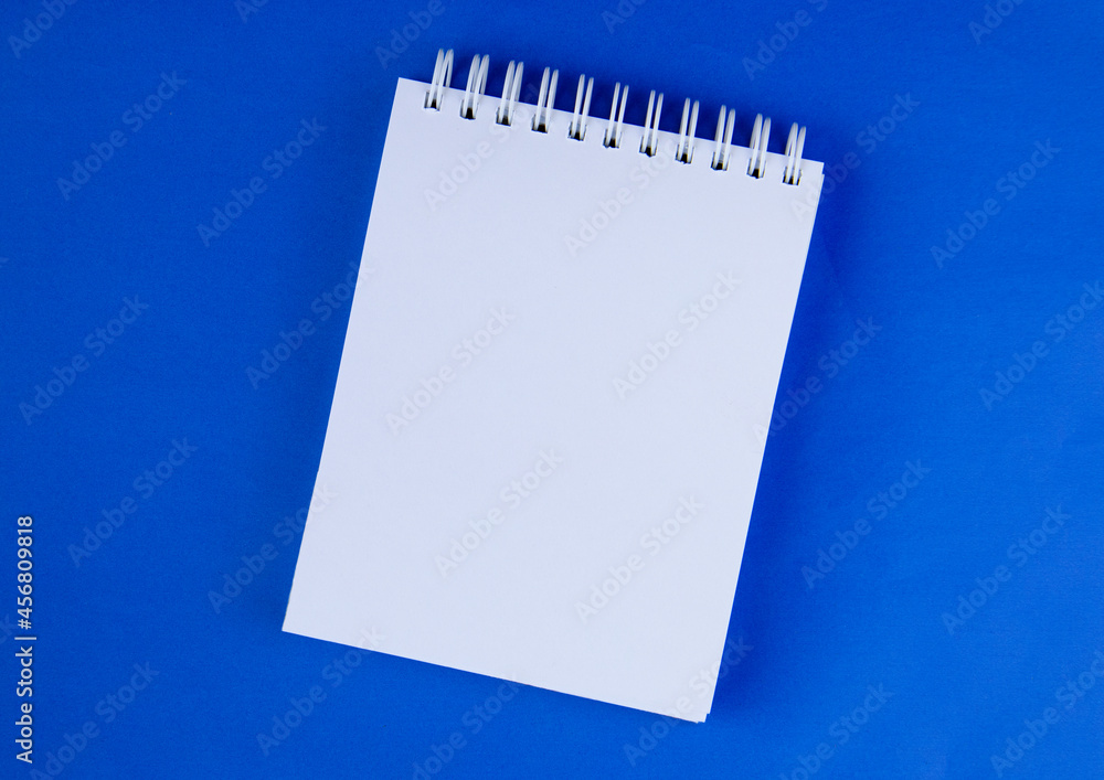 a white notebook on a blue background. Space for text a white notebook on a blue background. Space for text