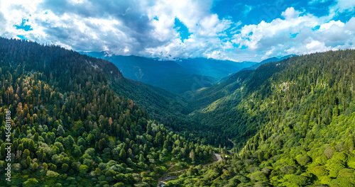a large aerial panorama of a mountain gorge and trails below in the park of waterfalls among the mountains of the Caucasus overgrown with green forests photo
