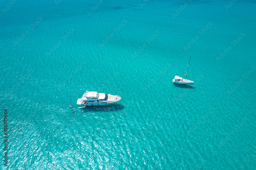 Aerial view of two yachts in turquoise water in Mediterranean Sea next to Sardinia island, La Pelosa beach