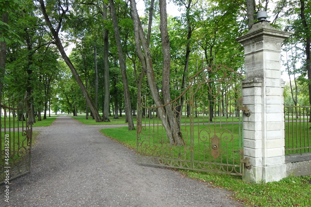 Fototapeta premium Open old wrought metal gates in Park Kadriorg on a summer. A lot of green grass and trees on the back. Tallinn, Estonia, Europe. August 2021