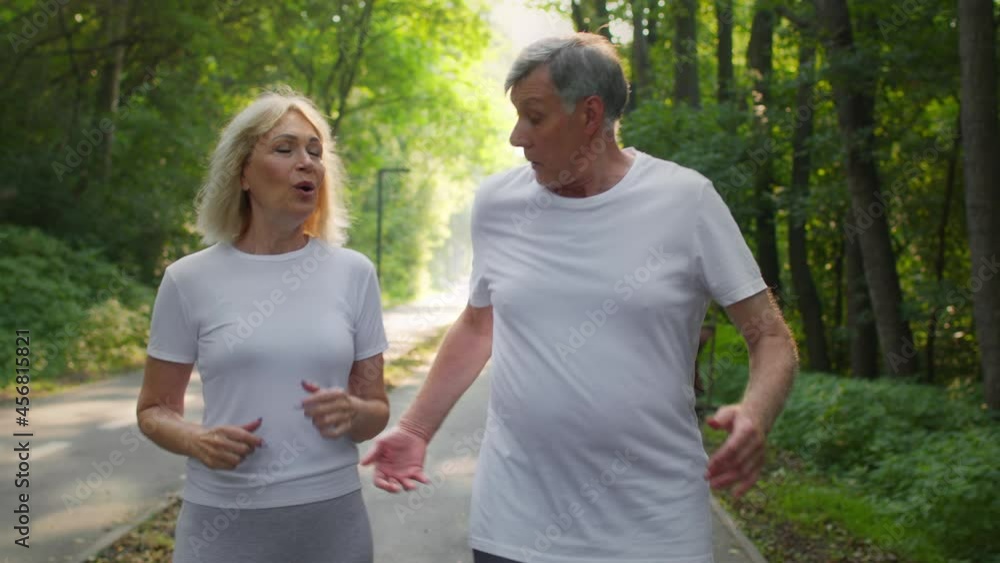 Active lifestyle on retirement. Sporty senior man and woman running together in public park, taking break and talking Active lifestyle on retirement. Sporty senior man and woman running together in public park, taking break and talking