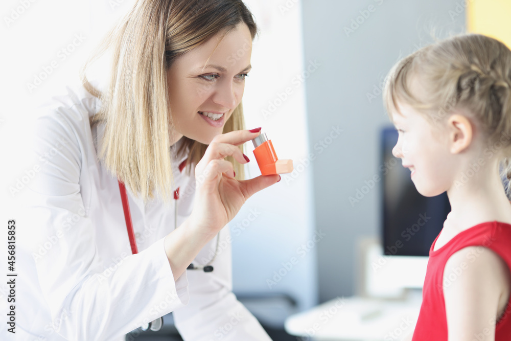 Pulmonologist doctor holding hormonal inhaler in front of little girl in clinic. - obrazy, fototapety, plakaty 