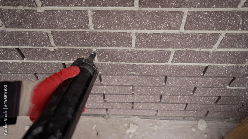 Repair in apartments and houses concept. The master sews seams on the brickwork. Joints in brickwork. Grouting with tiling fugue.