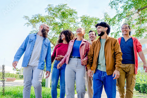 multiethnic group of friends walking in the street outdoors laughing and having fun. diverse people celebrating life together enjoying happy holidays. lifestyle, travel, togetherness and joy concept