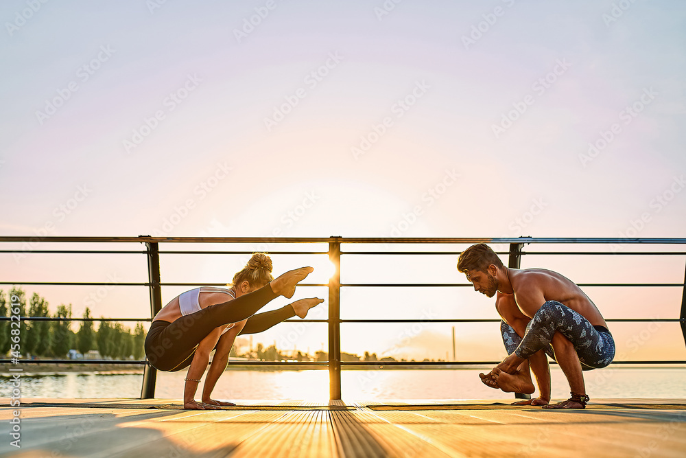 Obraz premium Couple practicing acrobatic yoga together on nature outdoors at sea.