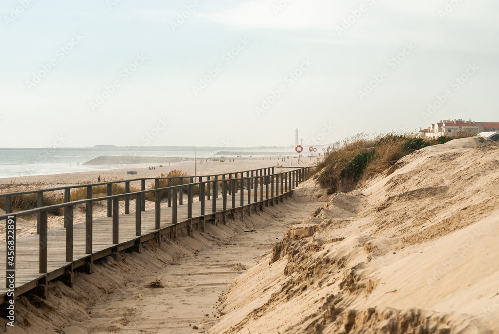 Dunes on the beach with a wooden pathway all along at a foggy seaside - Costa Nova, Portugal
