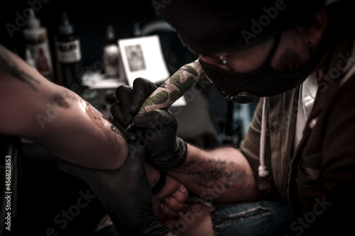 A professional tattoo artist makes a tattoo on a woman's hand.