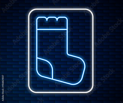 Glowing neon line Baby socks clothes icon isolated on brick wall background. Vector