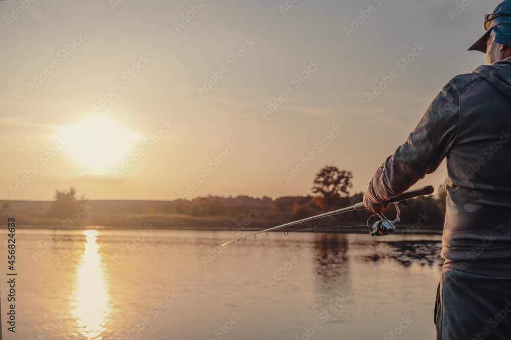 Fishing rod with a spinning reel in the hands of a fisherman. Fishing background