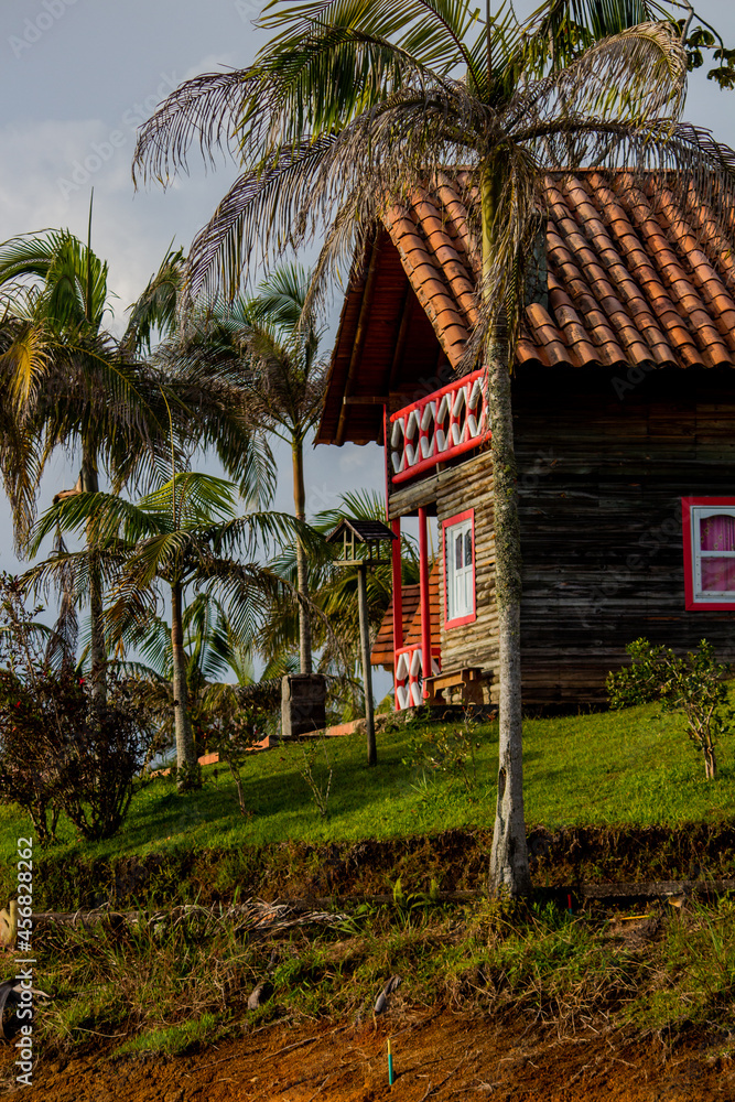 Tropical beautiful beach house with red and white windows on tropical island with palms on the beach of Caribian sea Tropical beautiful beach house with red and white windows on tropical island with palms on the beach of Caribian sea