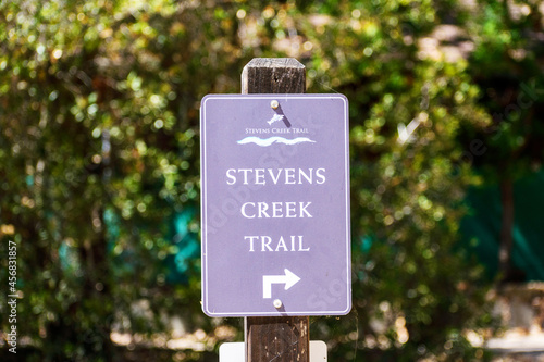 Stevens Creek Trail direction sign in San Francisco Bay Area. Blurred green trees background. - Mountain View, California, USA - 2021 photo