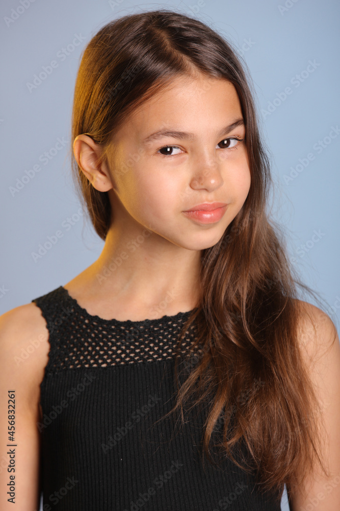 Close-up portrait of a bright charming dark-haired teenager girl 12 years old in black, she smiles sweetly and looks eye to eye. Close-up portrait of a bright charming dark-haired teenager girl 12 years old in black, she smiles sweetly and looks eye to eye.