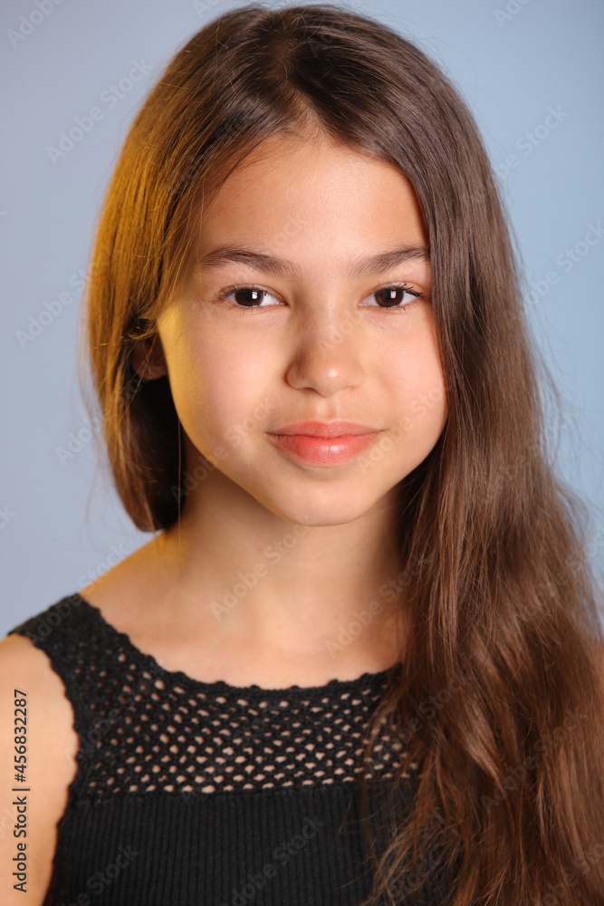 Close-up portrait of a bright charming dark-haired teenager girl 12 years old in black, she smiles sweetly and looks eye to eye. Close-up portrait of a bright charming dark-haired teenager girl 12 years old in black, she smiles sweetly and looks eye to eye.
