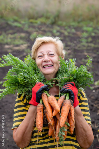 happy elderly woman showing her carrot harvest