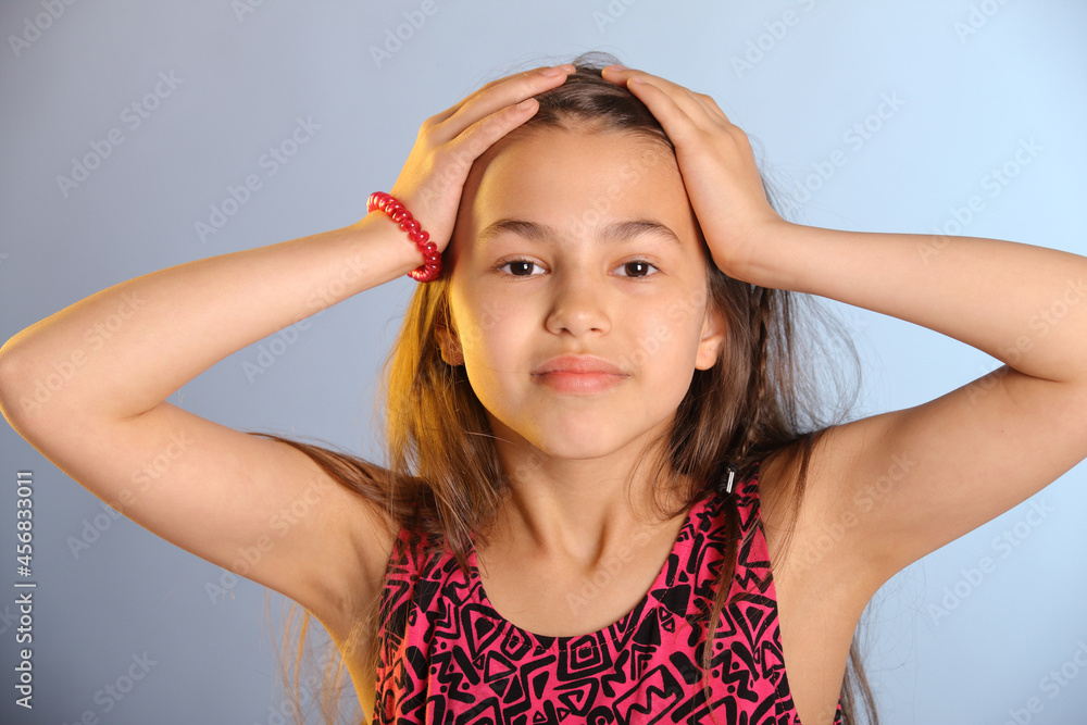 Portrait of a bright cute dark-haired teenage girl 12 years old in a purple dress, she is holding her head with her hands. Portrait of a bright cute dark-haired teenage girl 12 years old in a purple dress, she is holding her head with her hands.