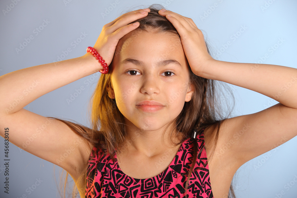 Portrait of a bright cute dark-haired teenage girl 12 years old in a purple dress, she is holding her head with her hands. Portrait of a bright cute dark-haired teenage girl 12 years old in a purple dress, she is holding her head with her hands.