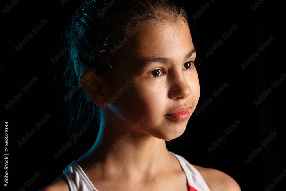 Close-up portrait of a bright beautiful brunette girl 12 years old on a black background. She has slicked hair and looks away. Close-up portrait of a bright beautiful brunette girl 12 years old on a black background. She has slicked hair and looks away.