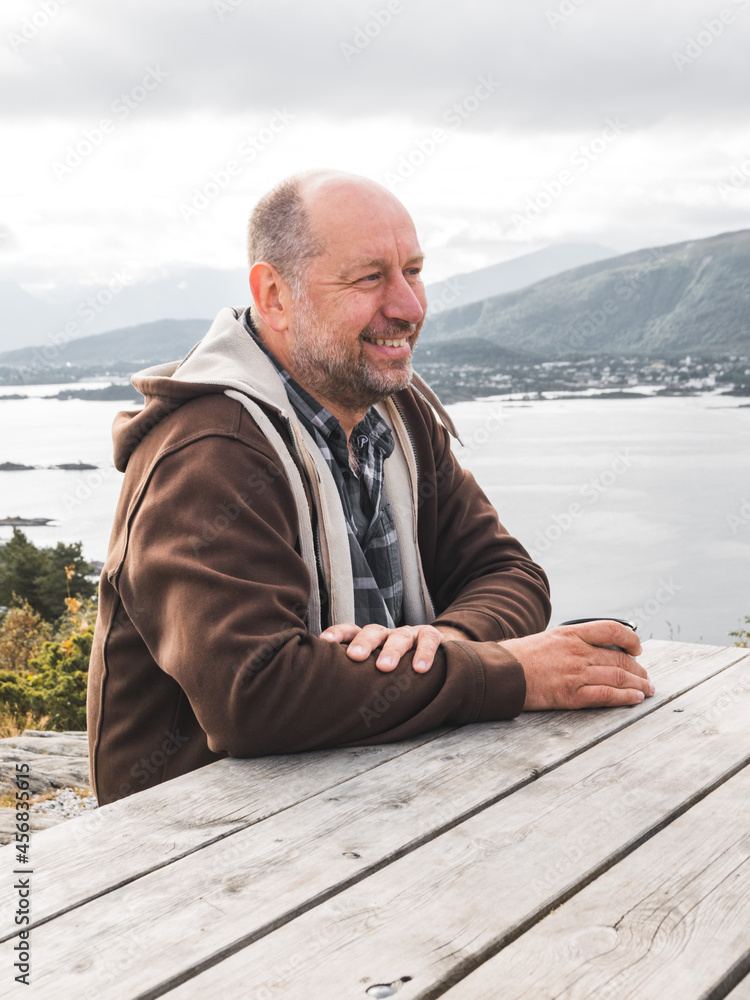 Φωτογραφία Beautiful shot of a middle-aged half bald Caucasian man sitting in a park in fro
