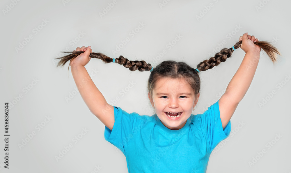 Happy child holding pigtails and laughing Happy child holding pigtails and laughing