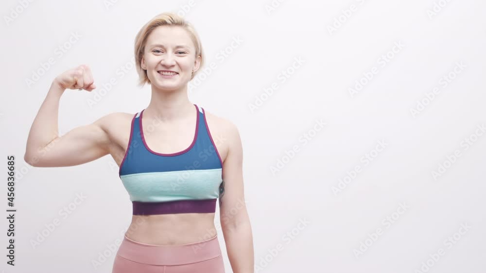 Young blond woman in activewear flexing her muscle Young blond woman in activewear flexing her muscle