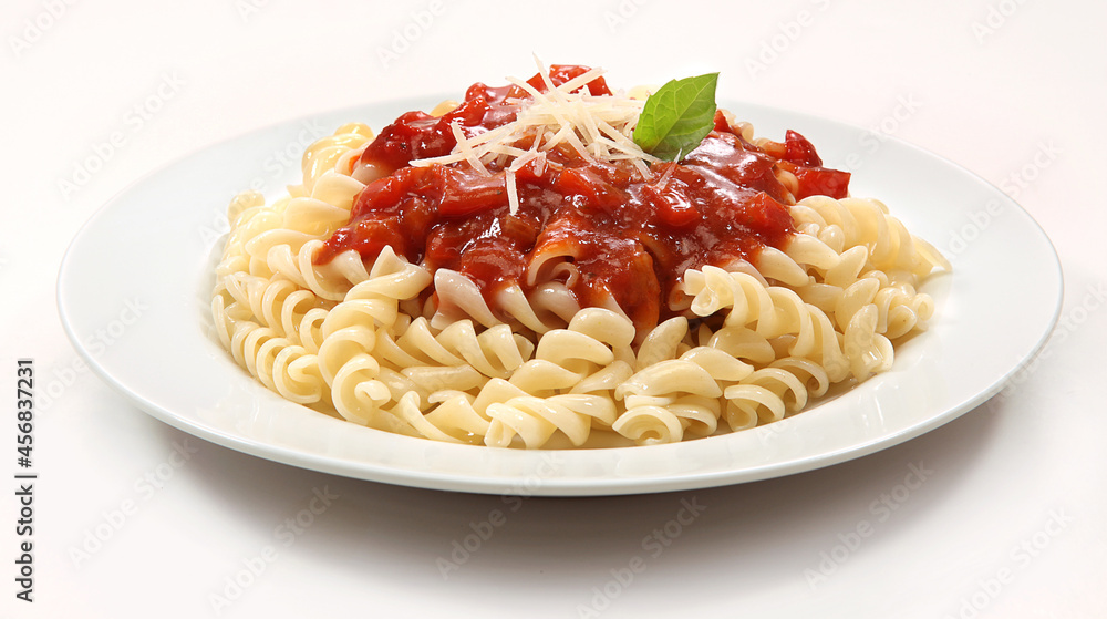 Massa tipo parafuso com molho de puro tomate com detalhe de queijo parmesão e folha de manjericão em fundo branco para recorte. Massa tipo parafuso com molho de puro tomate com detalhe de queijo parmesão e folha de manjericão em fundo branco para recorte.