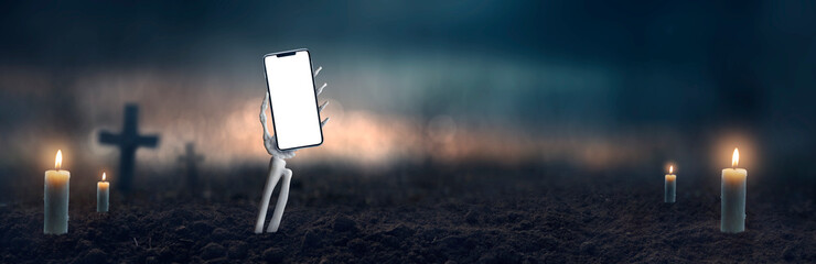 hand of a skull coming out of the ground holding a cell phone on halloween night