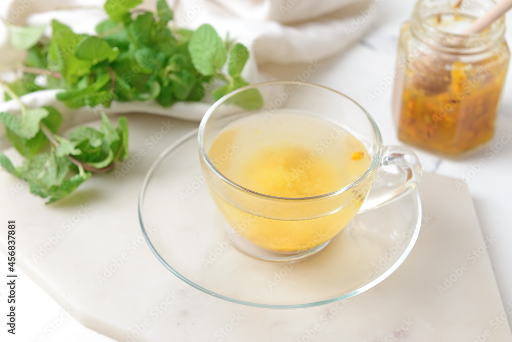 Cup of tasty tea with sea buckthorn on light background Cup of tasty tea with sea buckthorn on light background