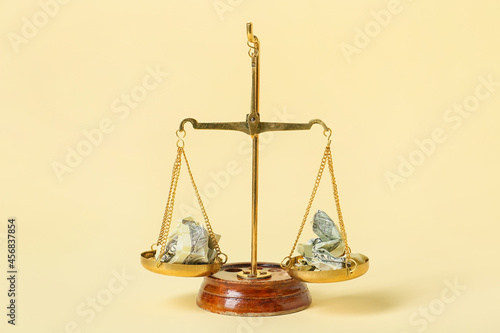 Scales of justice with crumpled dollar banknotes on color background