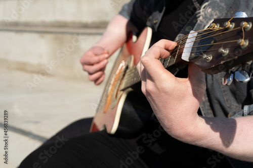 Close-up of a white man playing guitar in the public square.