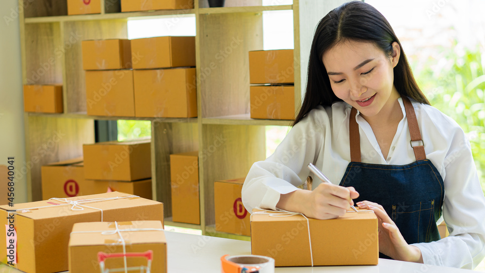 young businesswoman working at home on online business Women business owners use laptops to work at home and start an SME business. Small and cardboard boxes at the workplace young businesswoman working at home on online business Women business owners use laptops to work at home and start an SME business. Small and cardboard boxes at the workplace