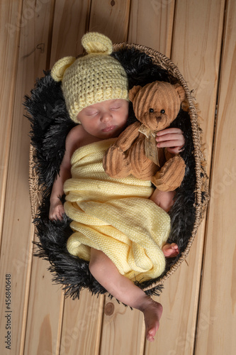bebé recién nacido durmiendo con osito de peluche en un canasto photo