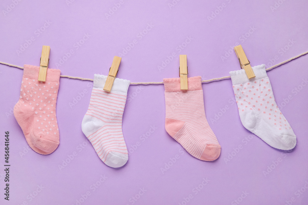 Different baby socks hanging on rope against color background Different baby socks hanging on rope against color background