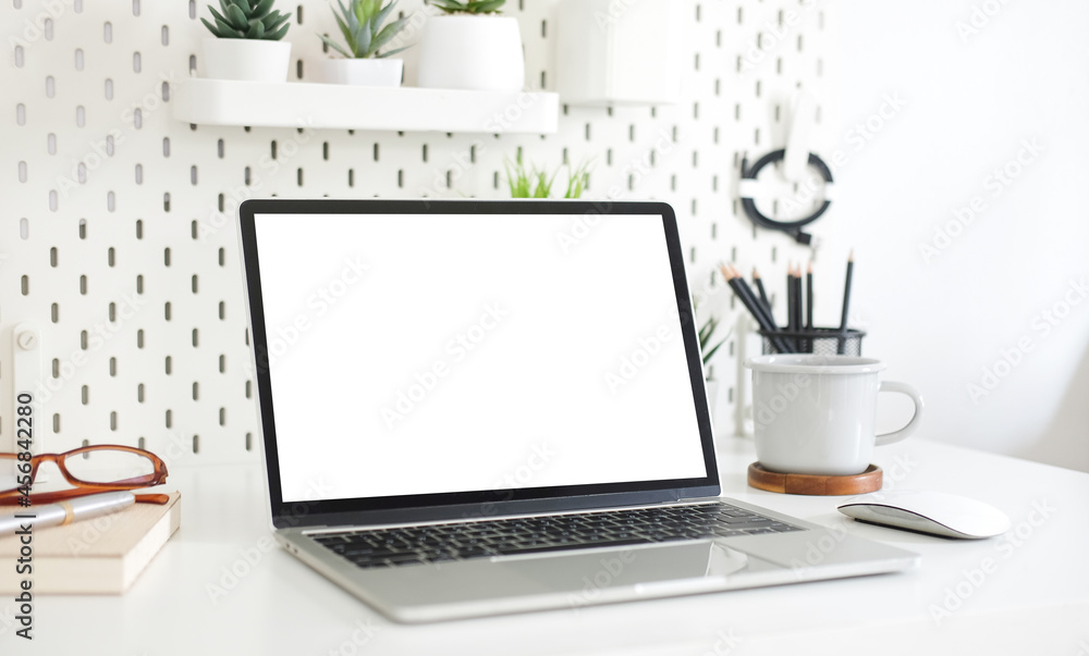 Creative workspace with blank screen on white table.