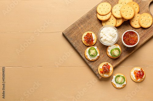 Delicious crackers with cottage cheese and jalapeno pepper jam on color wooden table