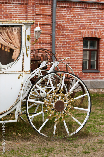 Old white carriage on the background of a red brick building