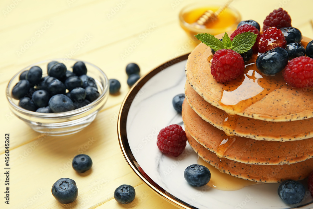 Plate of tasty pancakes with honey and berries on color wooden background, closeup Plate of tasty pancakes with honey and berries on color wooden background, closeup