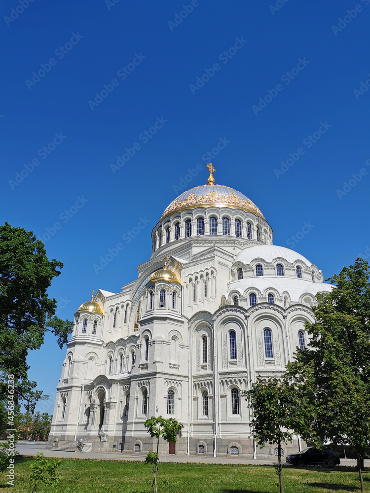 St. Nicholas Cathedral among the trees against the background of a cloudless sky, on a summer day in Kronstadt.