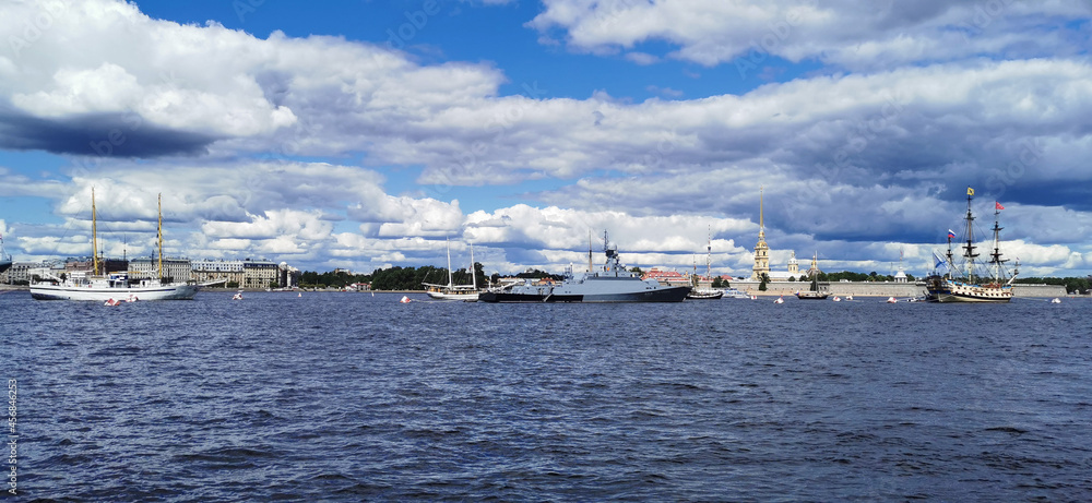 Panoramic view of the warships, frigates and sailboats built in the Neva water area for the Day of the Navy in St. Petersburg, there are many pleasure boats around.