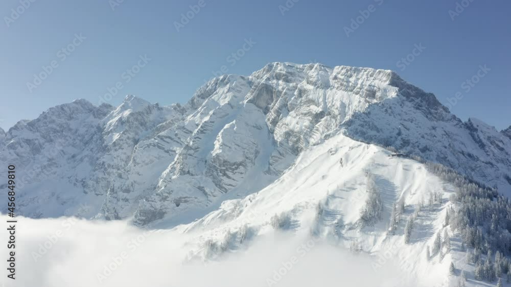 Aerial view through fog and over snowy trees, away from alpine peaks - reverse, drone shot Aerial view through fog and over snowy trees, away from alpine peaks - reverse, drone shot