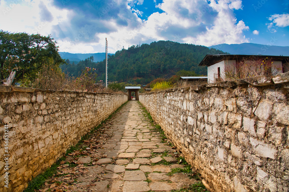 Stone-paved alleys. Walls made of earth and white stone blocks. A corner of a Buddhist temple, Bhutan. November 2019
